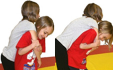 Una bambina solleva sulla propria schiena una compagna, prendendole un braccio davanti al petto.