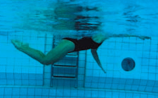 Une athlète nage en crawl waterpolo avec des battements de jambes du dauphin.