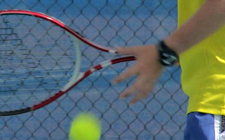 Detailaufnahme: Ein Kind prelt einen Ball, man sieht einen halben Tennisschläger.