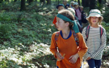Dei bambini camminano in fila indiana su un sentiero in un bosco.