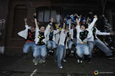 Dei giovani che indossano jeans e giacche bianche saltano con le mani tese verso l'alto
