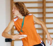 Un jeune homme lance un frisbee dans une salle de sport.