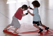 Deux enfants luttent sur un tapis.