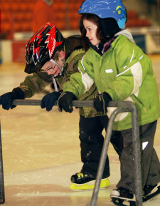 Due bambini sul ghiaccio spingono una mini porta 