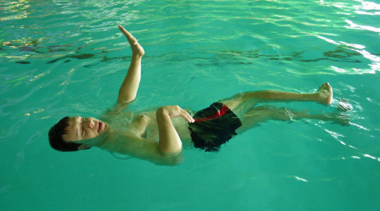 Un bambino portatore di andicap nuota in una piscina