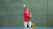 Une jeune fille jongle avec trois balles.