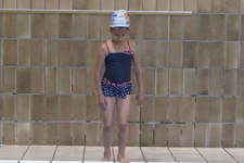 Una bambina si prepara a eseguire il tuffo dal bordo della piscina