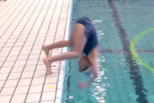Una bambina esegue una capriola in avanti dal bordo della piscina