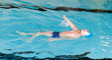 Un enfant nage sur le dos.