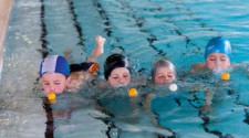 Foto: quattro bambini nuotano soffiando su una pallina per farla avanzare