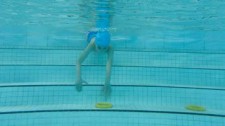 Foto: un bambino s'immerge dai gradini della piscina per recuperare degli anelli
