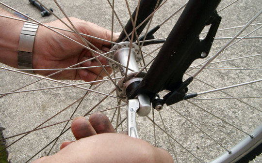 Gros plan sur deux mains ajustat la roue d'un vélo.
