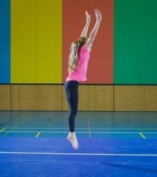 Foto: una ragazzina esegue un salto in verticale con le braccia alzate