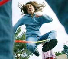 Ein Mädchen springt über ein Gummiseil.