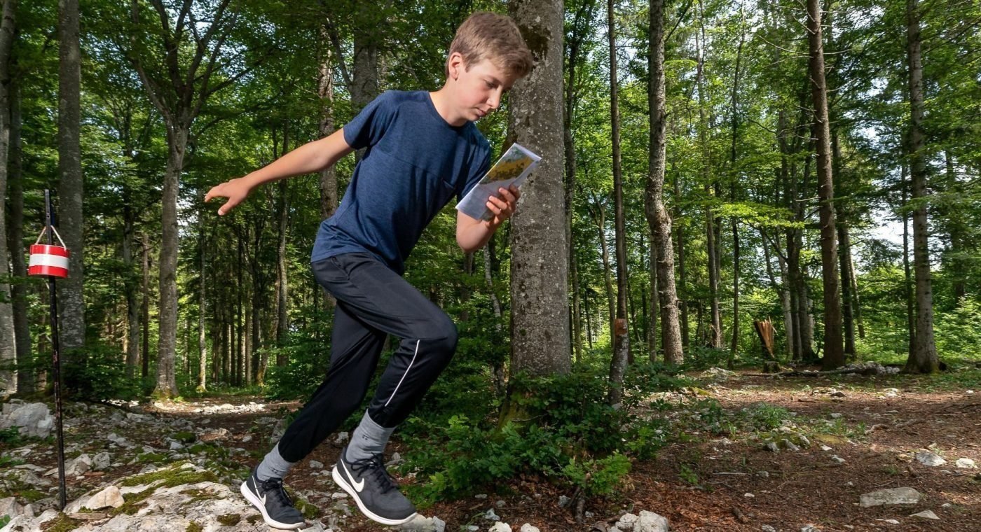 Junger Athlet beim OL im Wald.