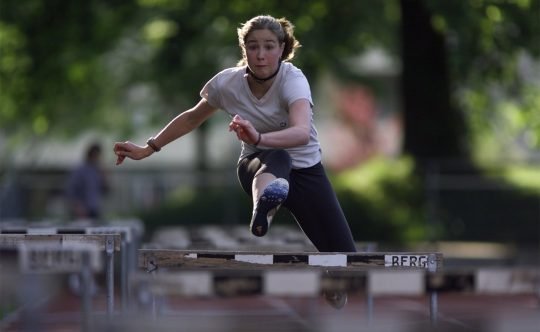 Athletin springt über eine Hürde