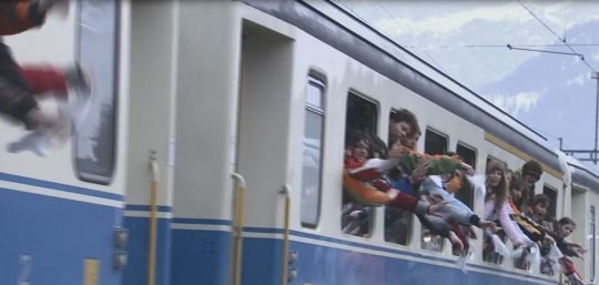 Photo: des enfants sont dans un train et font signe de la main.