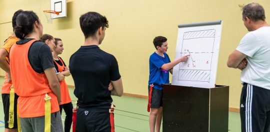 Un jeune explique une stratégie sur un flip-chart à ses coéquipiers.