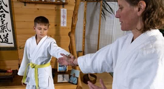 Lehrperson bei einem Aikido-Griff mit einem jungen Schüler.
