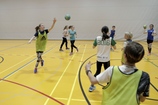Des jeunes jouent avec des ballons dans une salle de sport.