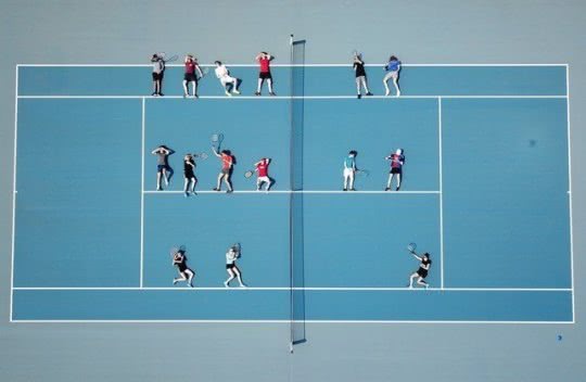 Foto von Oben: Schülerinnen und Schüler liegen auf einem Tennisplatz. 