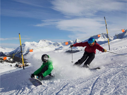 Due ragazzi sulla neve, uno con gli sci, l'altro con lo snowboard
