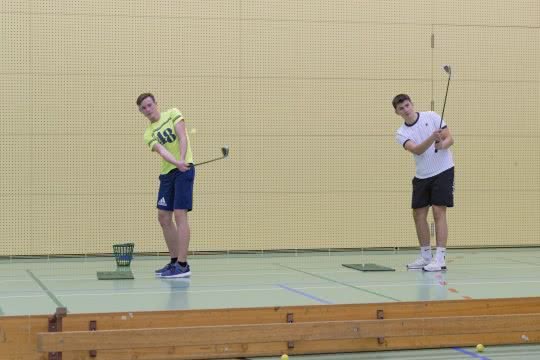 Deux jeunes tapent une balle de golf par-dessus un banc suédois.