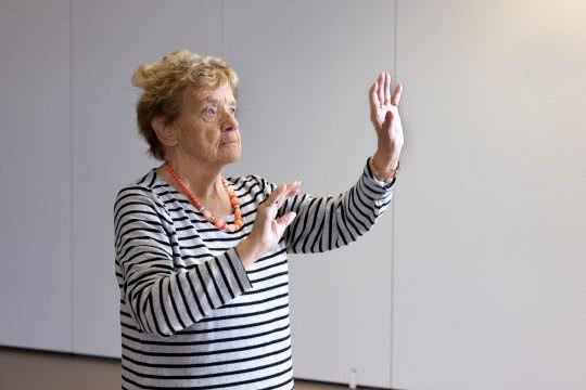 Eine ältere Dame führt eine Pantomimen-Übung aus.