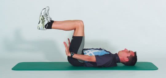 Une sportif démontre la position initiale d'un exercice de musculature des abdominaux.