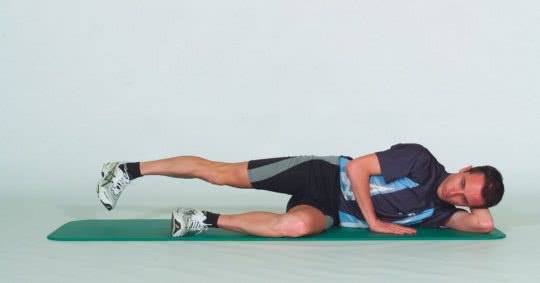 Une sportif démontre la position initiale d'un exercice de musculature des abducteurs.
