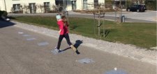 Una bambina corre su dei fogli quadrati posati per terra