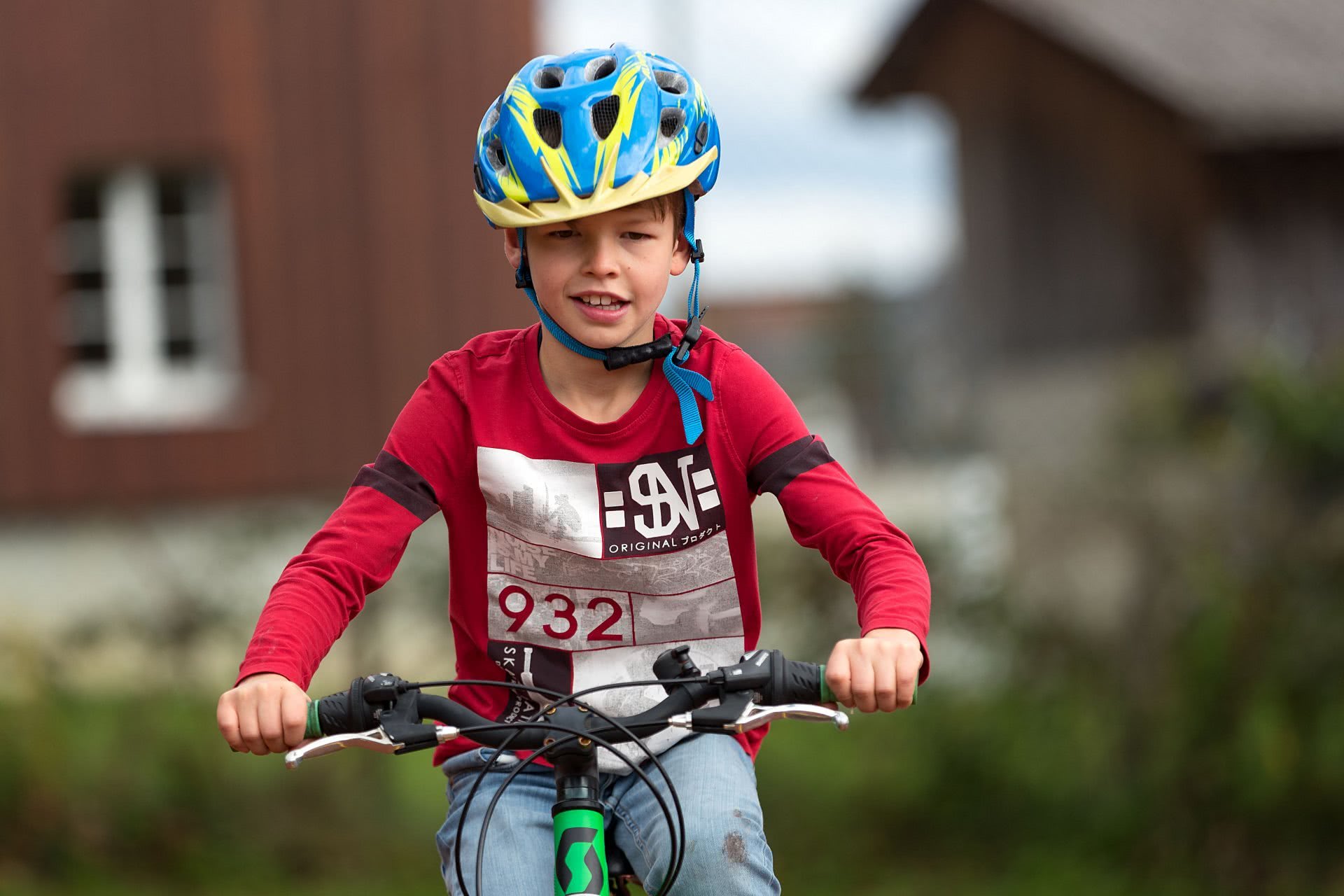 Un bambino in bicicletta, che indossa il casco