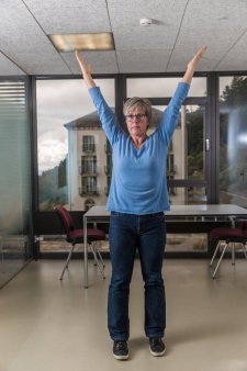 Una donna in piedi in un ufficio tende le braccia in alto