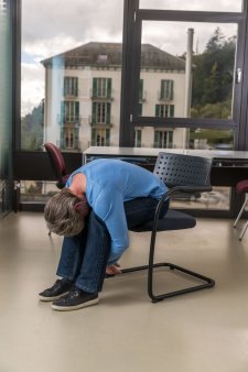 Una donna seduta su una sedia da ufficio si piega in avanti e lascia cadere testa e braccia