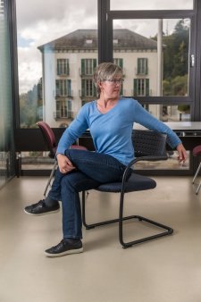 Una donna seduta su una sedia da ufficio ruota la parte superiore del corpo verso sinistra