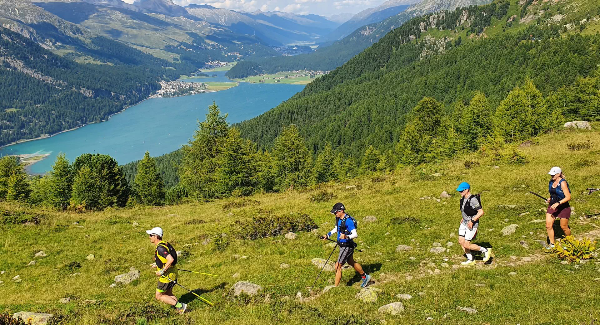 Un groupe de coureuses et coureurs de trail se suivent sur un sentier de montagne.