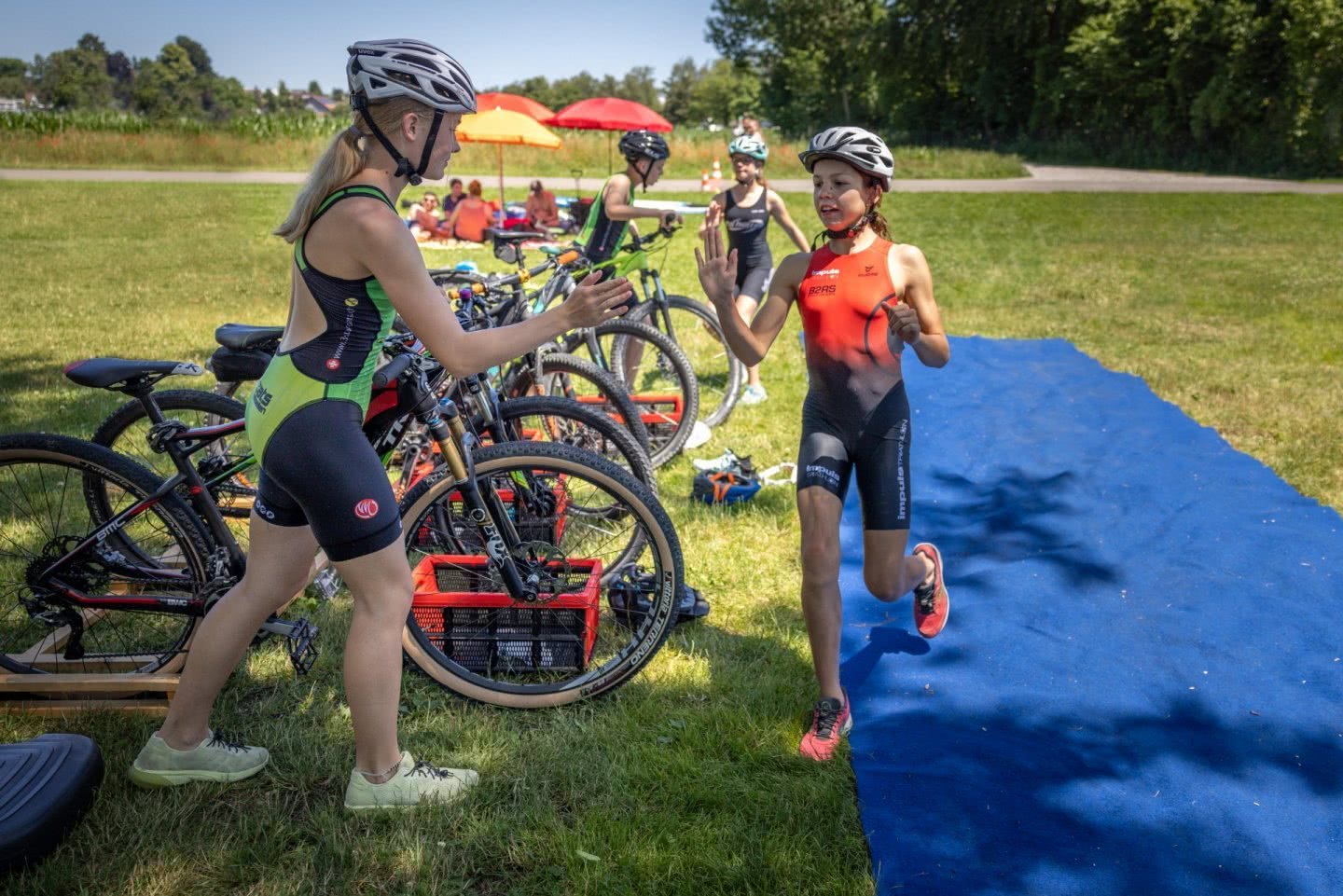 Deux jeunes filles se passent le relais dans la zone de transition.