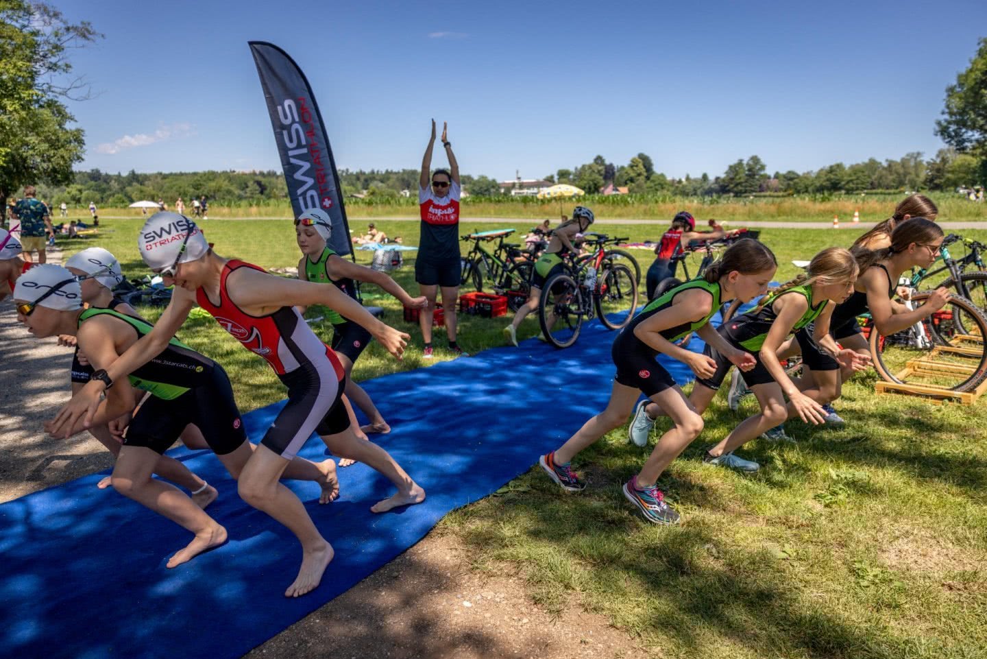 Trois groupes de jeunes filles s'élancent du même point de départ à pied, à vélo et en direction du lac pour nager.