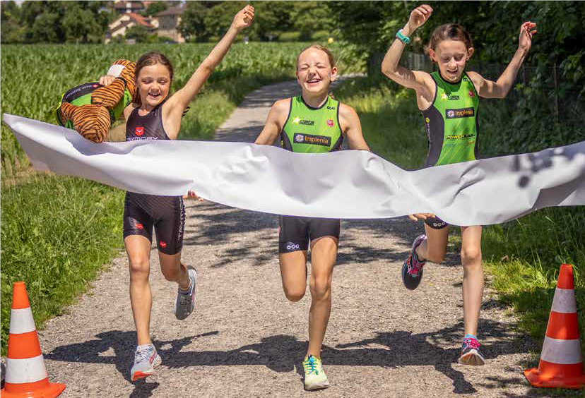 Photo: trois jeunes filles franchissent ensemble la ligne d'arrivée d'une course de triathlon