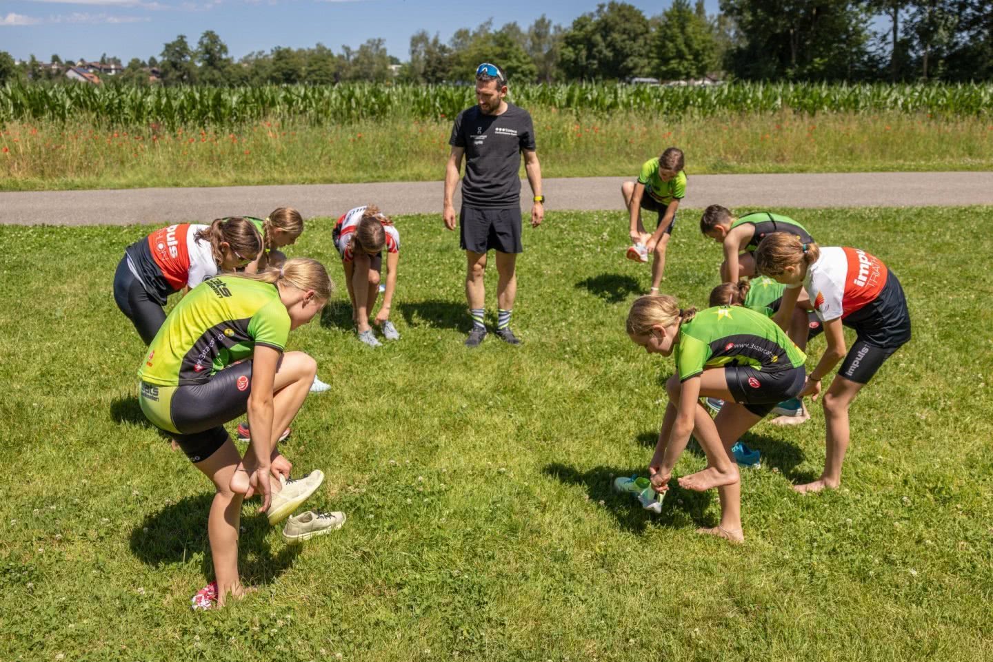 Des jeunes filles chaussent leurs chaussures sous le regard de leur entraîneur.