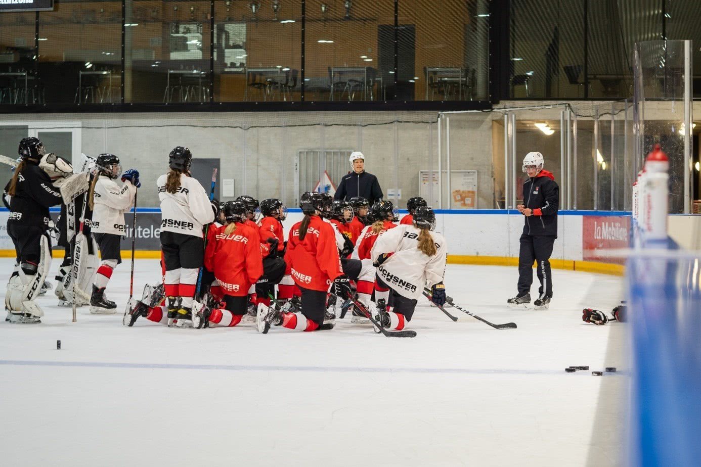 Un entraîneur s'adresse à des joueuses de hockey sur glace.
