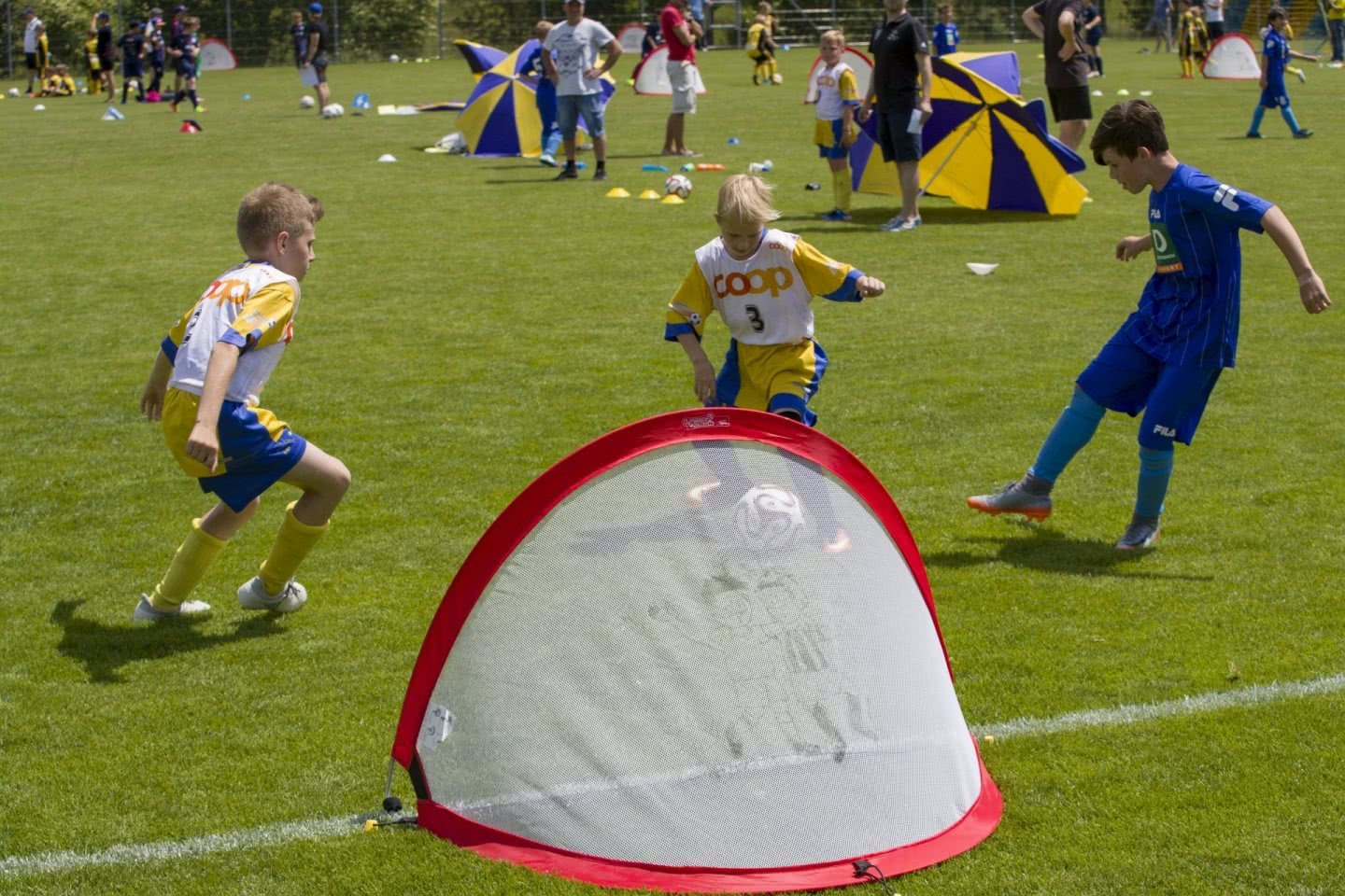 Des jeunes jouents au football sur un terrain.