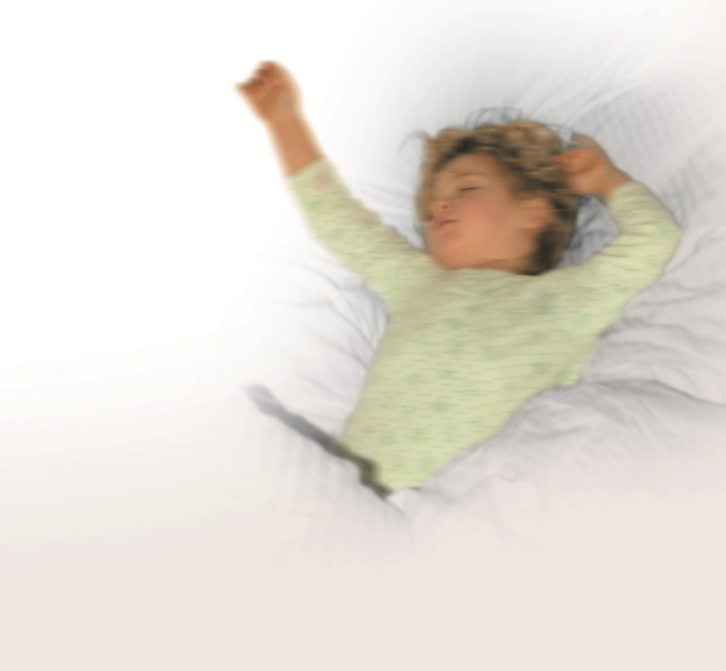 Foto: Kind liegt im Bett und streckt die Arme von sich.