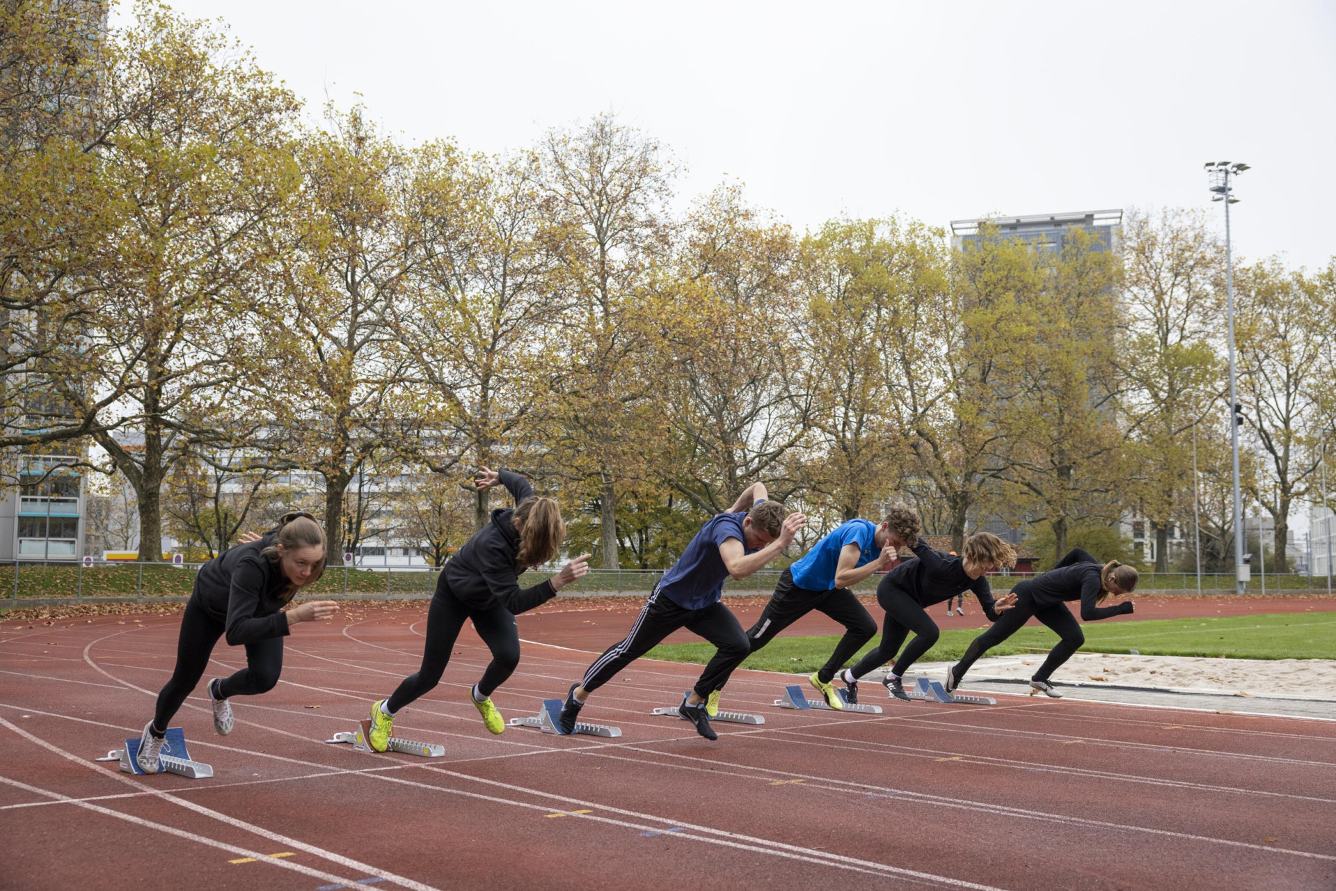 Foto von 6 Läufer:innen die aus dem Startblock starten.