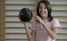 Foto: una ragazza ride prima di lanciare una palla nera