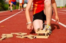 Foto: un bambino sta costruendo una torre con dei pezzi di legno su una pista di atletica leggera