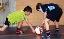 Due bambini sono chinati su una palla e cercano di muoverla con il pugno chiuso.