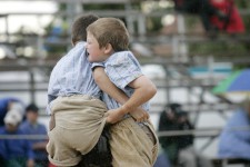 Due bambini lottano in piedi tenendosi per i pantaloni.