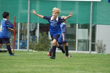 Un enfant lève les bras au ciel après avoir marqué un but.