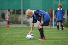 Un bambino dispone la palla sul campo e si prepara a rimetterla in gioco